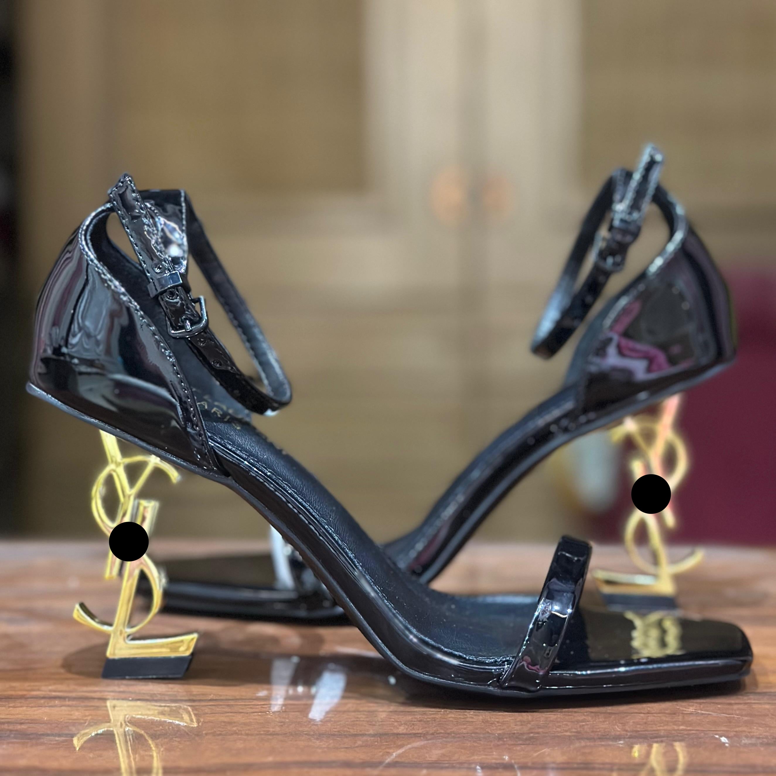Black high-heeled shoes on a wooden surface with blurred background